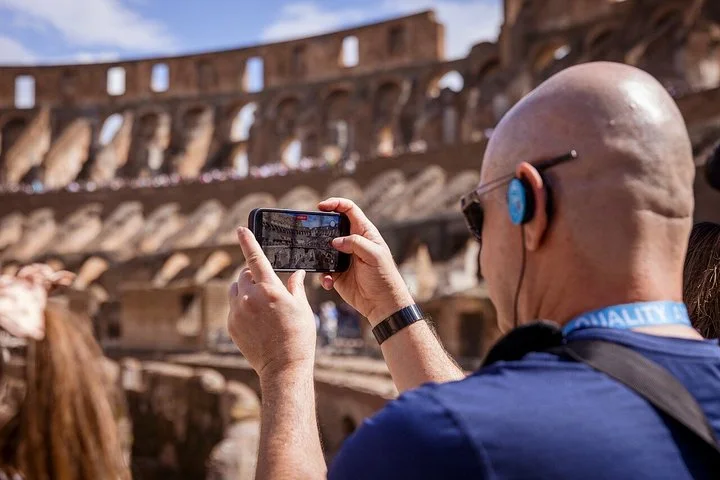 Visitor photographing the Colosseum interior with a phone