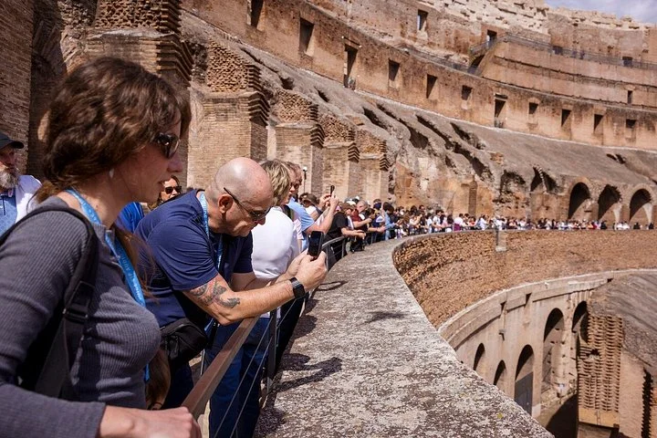 Visitors looking over a stone railing at the main Colosseum levels