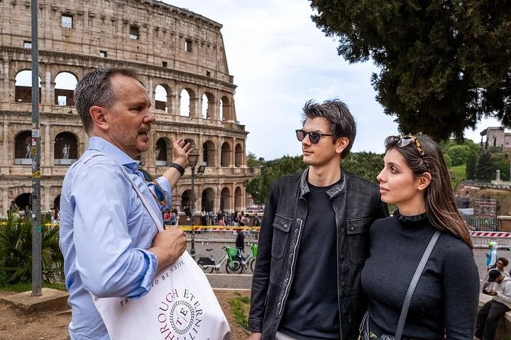 Guide speaking with two visitors beside the Colosseum exterior