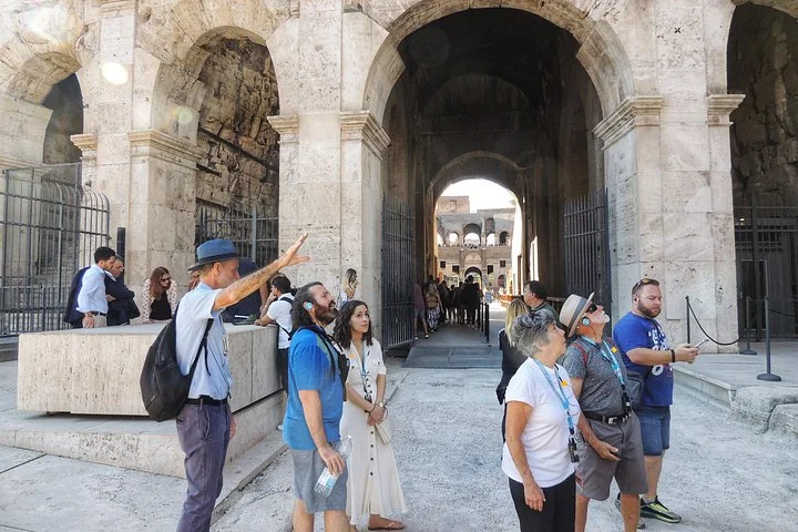 Guide and visitors beneath the Colosseum entrance arches