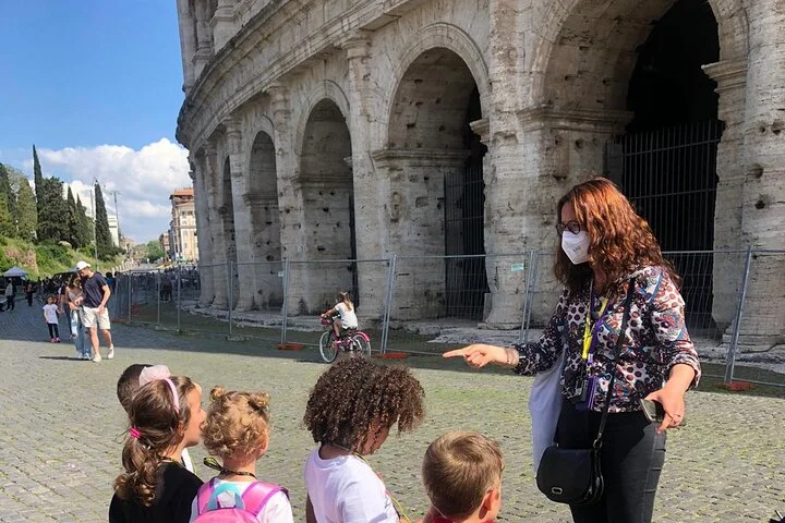 Guide speaking with children beside the Colosseum exterior