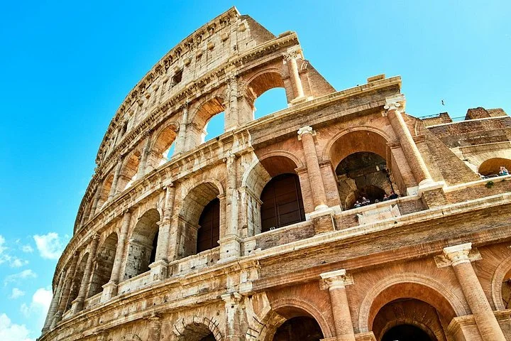 Golden Colosseum exterior arches beneath vivid blue sky