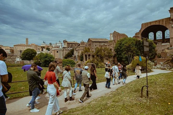 Visitors walking through the Roman Forum beneath a cloudy sky