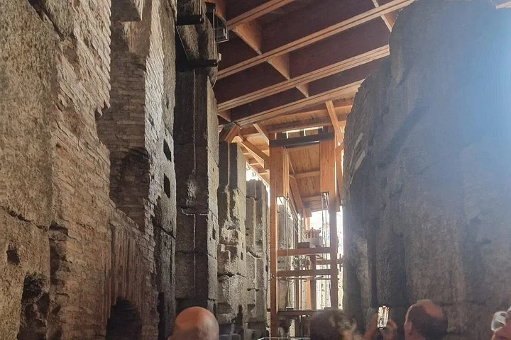 Timber lift structures rise between stone pillars beneath the arena.