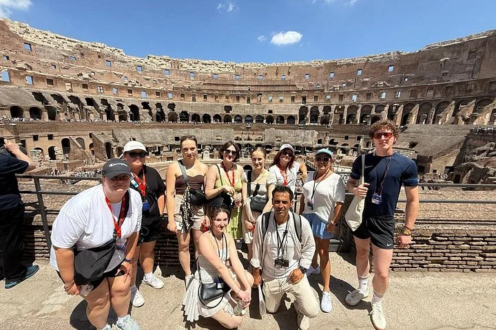 Visitors pose at a Colosseum overlook under a clear sky.