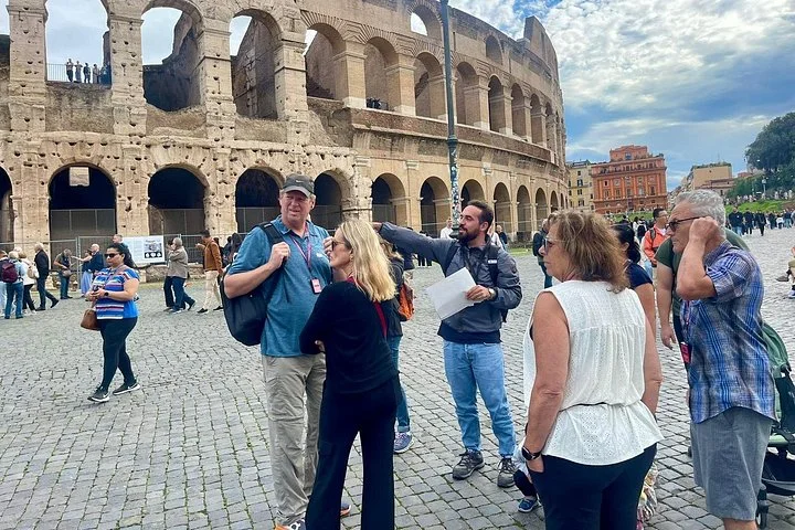 Guide and visitors beside the Colosseum exterior