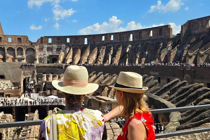 Two visitors in sunhats at a main-level Colosseum overlook