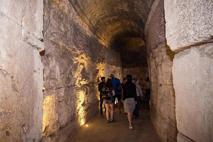 Visitors walk along a warmly illuminated underground passage.