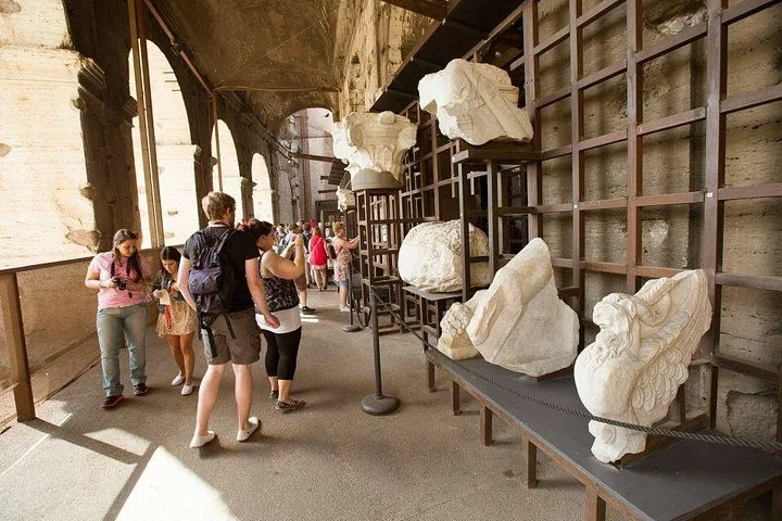 Visitors pass ancient stone fragments displayed in a Colosseum corridor.