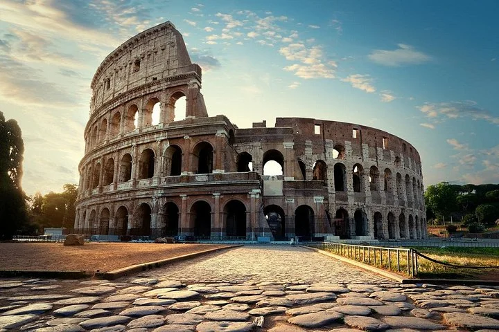 Colosseum exterior above cobbled paving in warm low light