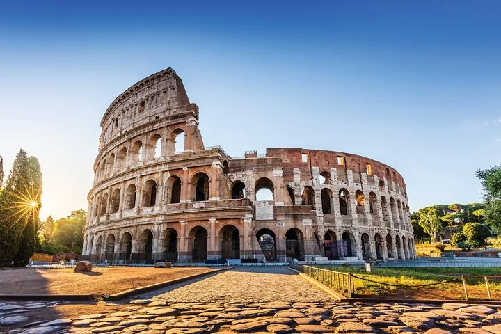 Colosseum exterior with a sunburst over the cobbled square