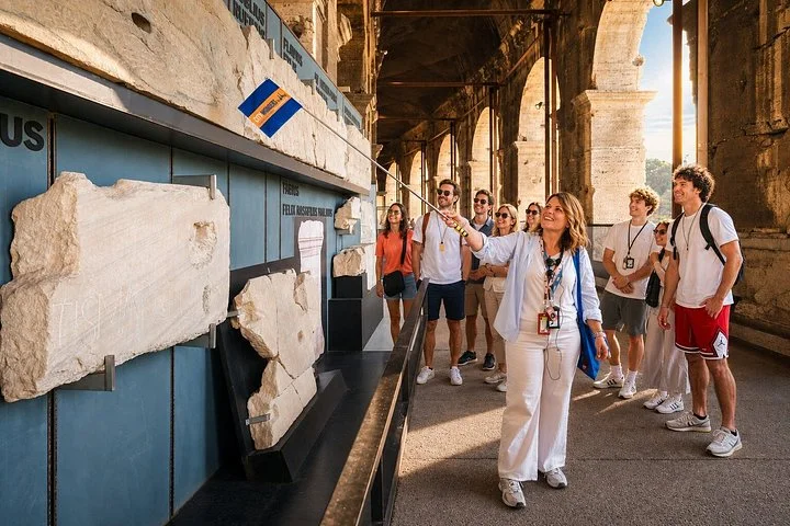 Guide and visitors beside museum displays in a Colosseum arcade