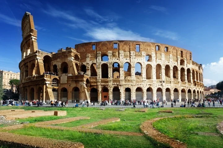 Colosseum exterior above green lawns under a vivid sky