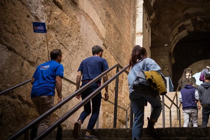 Guide and visitors ascending a Colosseum main-level staircase