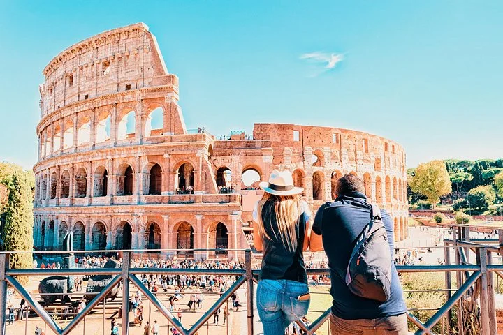 Two visitors looking toward the Colosseum from a public terrace