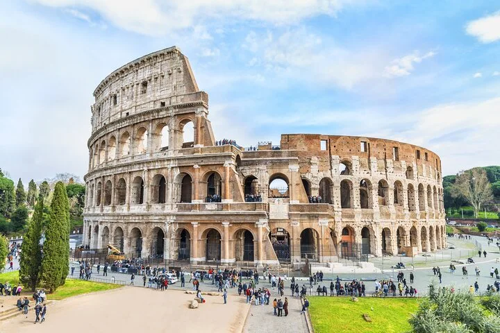 Wide sunlit Colosseum exterior with visitors in the public square