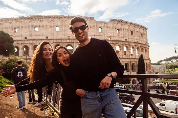 Travellers posing with the Colosseum behind them
