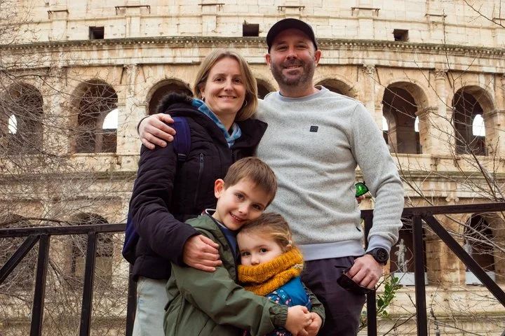 A family posing beside the Colosseum exterior
