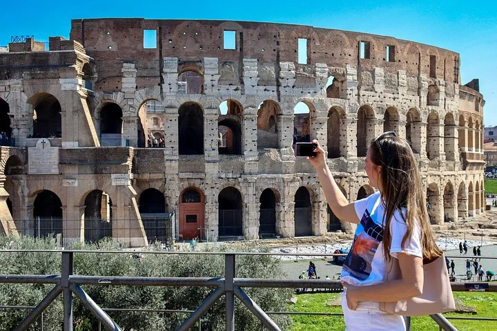 A visitor raising her phone beside the Colosseum