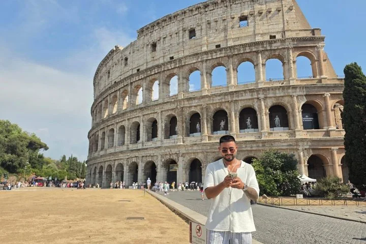 A visitor using a phone outside the Colosseum