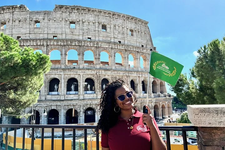 An Italy Wonders guide holds a green flag outside the Colosseum.