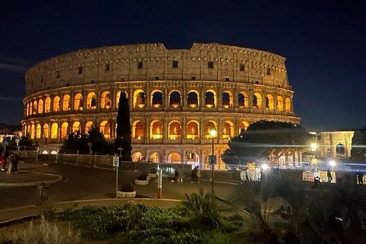 The illuminated Colosseum beside a night street
