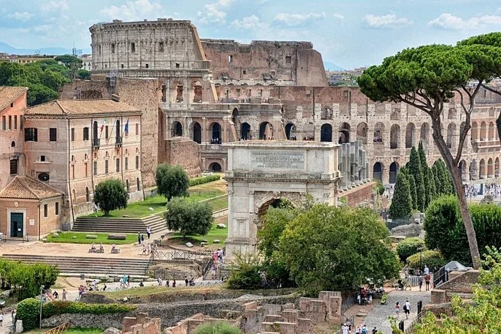 The Colosseum beyond Roman ruins and umbrella pines