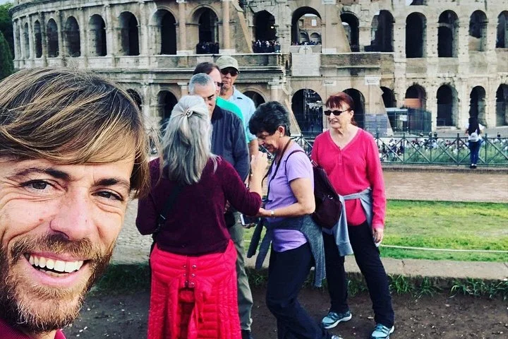 A guide and visitors beside the Colosseum facade