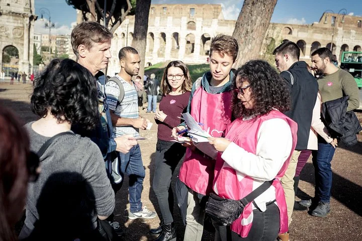 A guide checking details with visitors outside the Colosseum