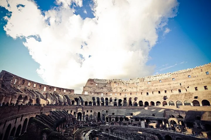 Colosseum tiers beneath large white clouds