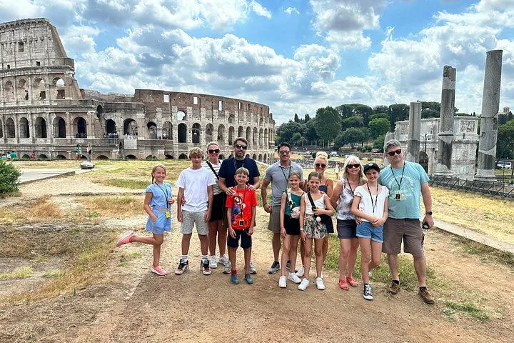 Visitors beside ancient columns with the Colosseum behind