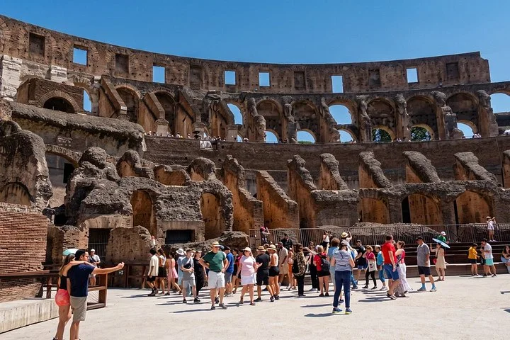 Visitors explore the Colosseum arena beneath its ancient arches.