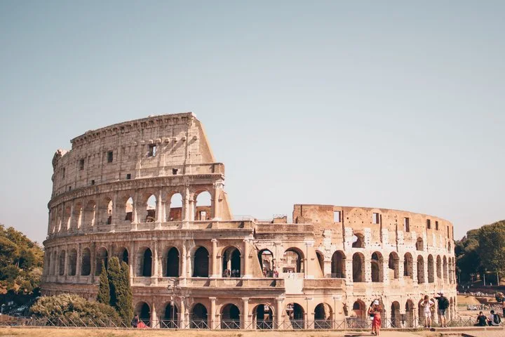 A wide sunlit view of the Colosseum exterior