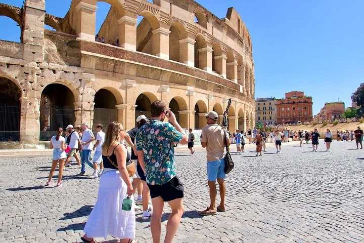 A guide and visitors pause outside the Colosseum facade.
