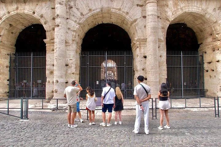 Visitors looking at the Colosseum’s entrance arches