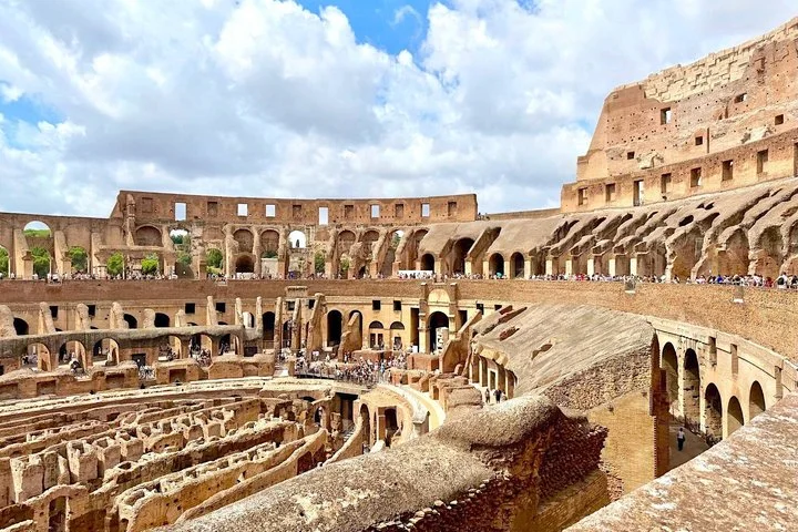 Upper Colosseum tiers and hypogeum under white clouds