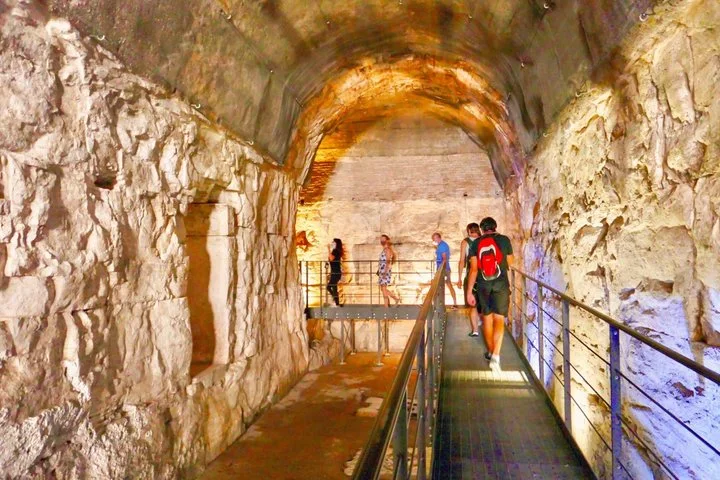 Visitors walk through an illuminated stone archway beneath the Colosseum.