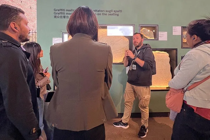 A guide explains ancient fragments displayed inside the Colosseum.