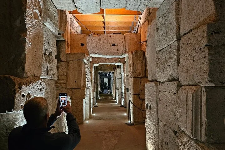 An illuminated stone corridor beneath the Colosseum arena.