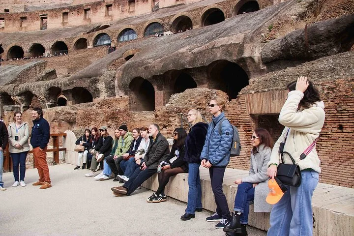 A guided group seated beside the Colosseum arena