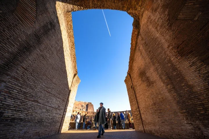 Visitors entering the Colosseum through a tall arch