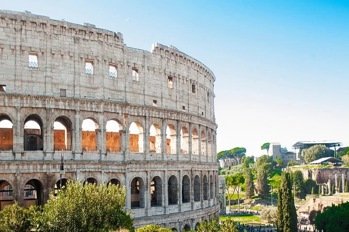 Colosseum arches and green Roman ruins in sunlight