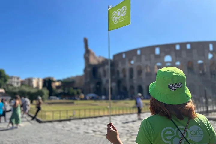 An EcoArt guide carries a green flag beside the Colosseum.