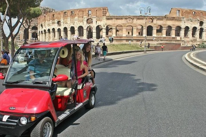 A red golf cart passing the Colosseum