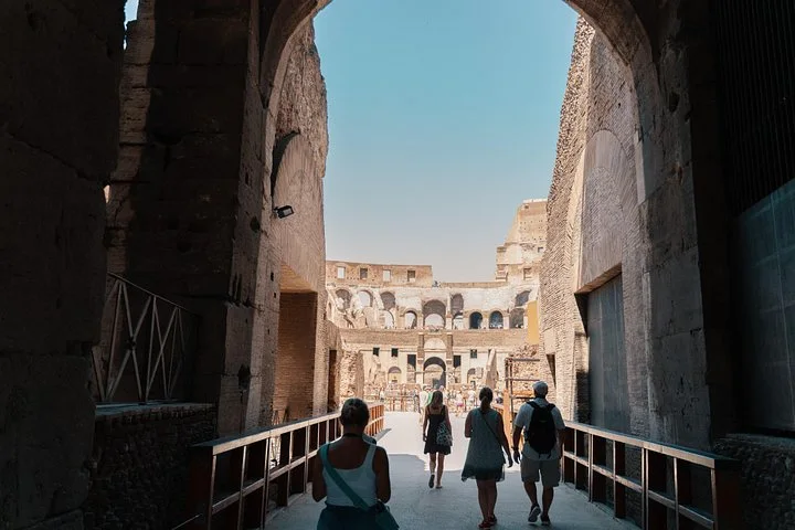 Visitors approach the Colosseum arena through a monumental arch.