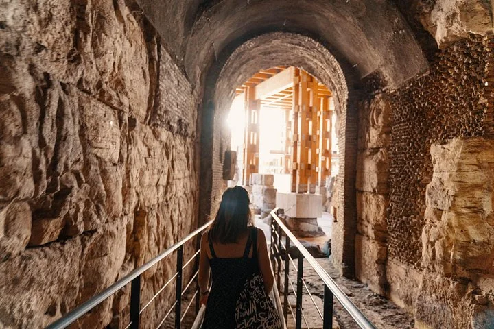 A visitor walks through an arched passage beneath the Colosseum arena.