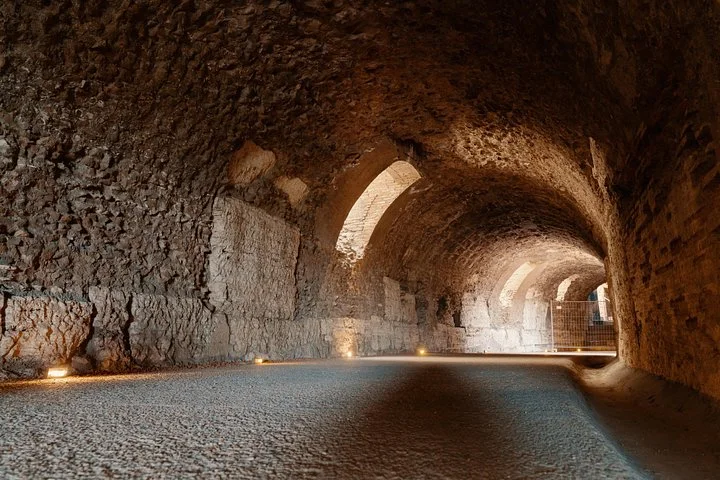 Low lights illuminate an empty vaulted underground corridor.