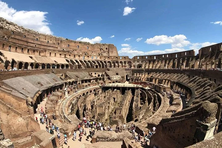 The Colosseum interior under a bright blue sky
