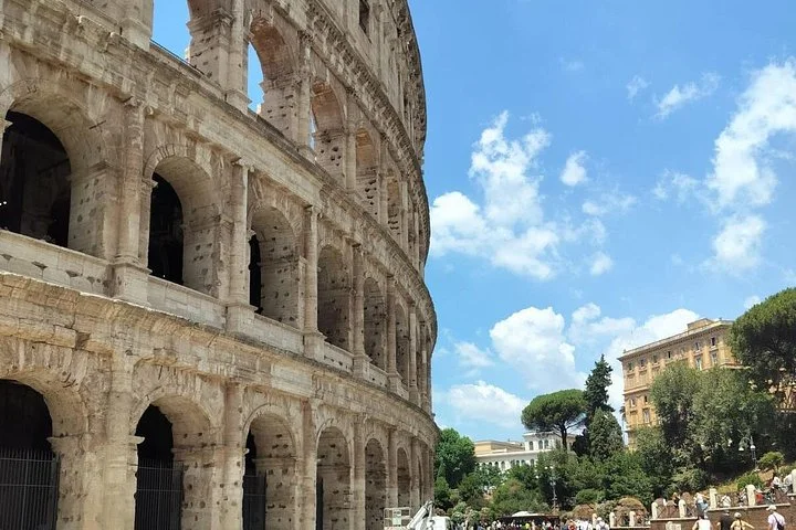 Visitors walking beside Colosseum stone arches