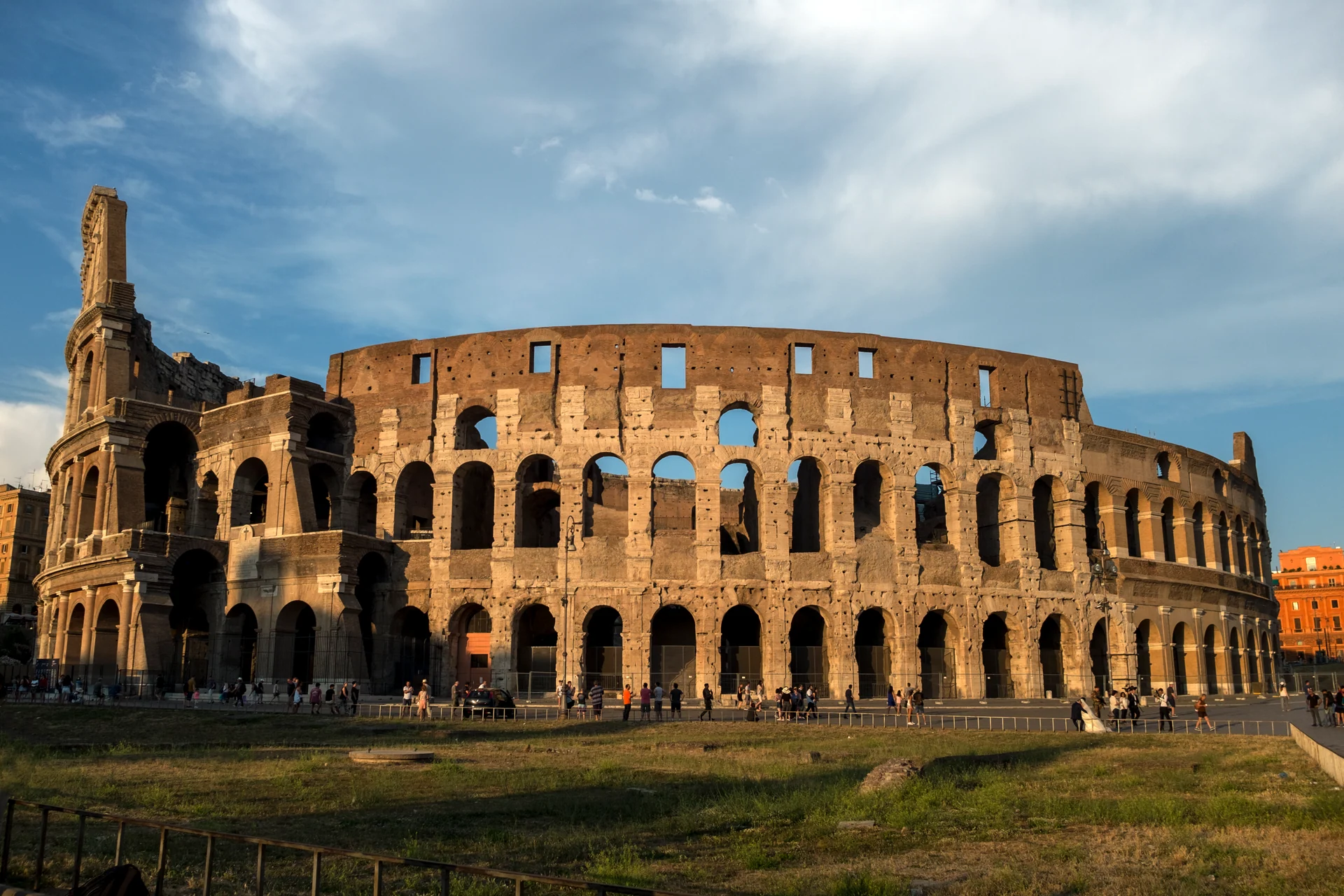 The Colosseum exterior in warm evening sunlight beneath a blue sky
